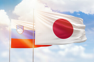 Sunny blue sky and flags of japan and slovenia