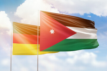 Sunny blue sky and flags of jordan and germany