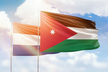 Sunny blue sky and flags of jordan and netherlands