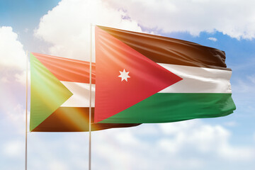 Sunny blue sky and flags of jordan and sudan
