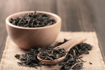 Dry black tea leaves in wooden bowl and spoon