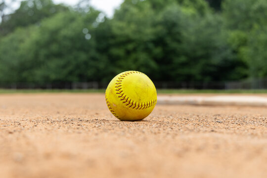 Close-up of softball in the dirt infield a softball or baseball field. Empty field used for sports teams.