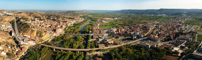 Fototapeta na wymiar General panoramic aerial view of Spanish town of Fraga on banks of Cinca river and its surroundings on sunny day, province of Huesca, Aragon