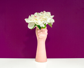 
white peonies in a pink vase on a white and lilac background with free space for text isolated