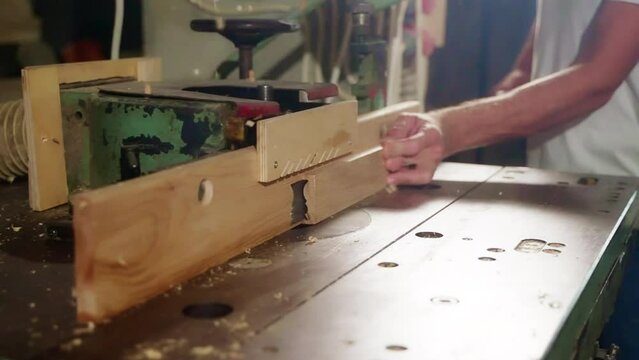 Carpenter making wooden mouldings with shaper machine