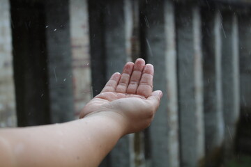 A woman cups her hands to catch the cold rain drops