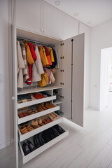 built-in wardrobe with hanging outerwear, garment and shoe shelves in white room - 511195479