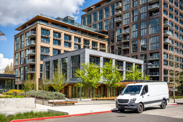 White compact cargo mini van for local delivery and small business standing on the urban city street with multilevel residential apartment buildings © vit