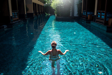Mujer joven disfrutando de piscina en hermoso resort de lujo