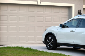 Car parked in front of wide garage double door on concrete driveway of new modern american house - Powered by Adobe