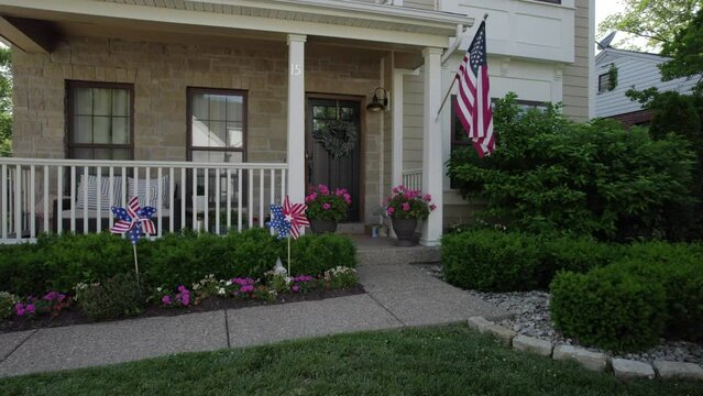 Camera drifts in front of a nice suburban house with an American flag and patriotic decorations.