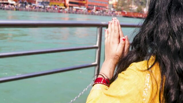 isolated young girl prying the holy ganges river at river bank from flat angle video is taken at ganga river bank haridwar uttrakhand india.