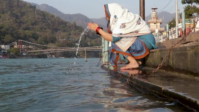 isolated young indian girl praying at ganges river bank from different angle video is taken at ganga river bank rishikesh uttrakhand india.