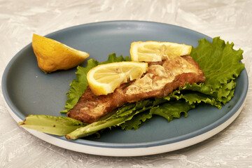 fried fish with lemon and herbs on a plate on the table