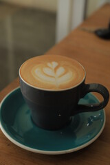 Cup of cappuccino with latte art, on brown table in cafe