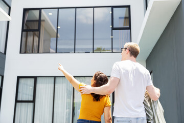 Portrait of back view family embracing together looking at their new house. Real estate and new home concept.