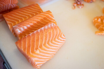 Raw salmon on white cutting board.