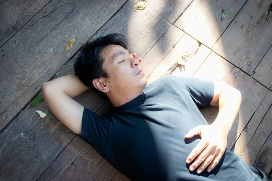 Asian man resting and relaxing on the old wooden floor under clear nature.