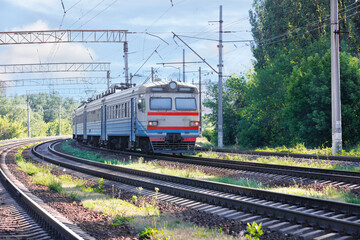 Fototapeta na wymiar An old train rushes along the railway leaving the city on a summer sunny day.