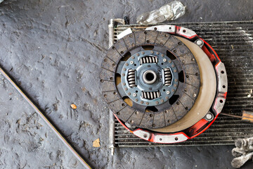 Old car brake disc on dirty garage floor, damaged car spare part, car service and maintenance concept