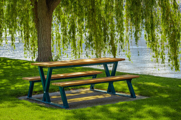 Empty wooden table with chairs in a summer park at the Lake. Sunny warm day by the lake. Summer...