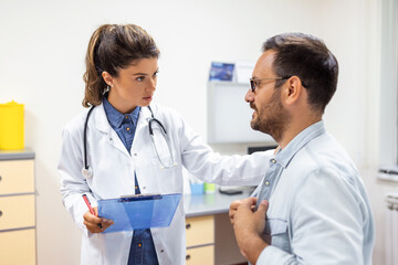 Experienced doctor discussing with patient his private medical file. Young man checking up with his MD, and consulting about the way of his health treatment and health insurance.