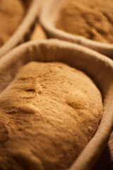 Process of making wheat bread at home. Proofing of the dough in rattan baskets. The concept of healthy homemade food. Vertical photo.