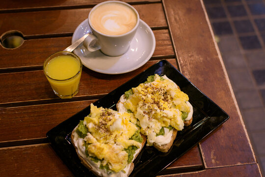 Desayuno saludable con caf&eacute;, jugo natural y tostadas de queso crema, palta y huevos revueltos. Nutrici&oacute;n equilibrada.
