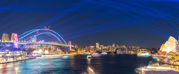 Naklejka premium Colourful Light show at night on Sydney Harbour NSW Australia. The bridge illuminated with lasers and neon coloured lights 