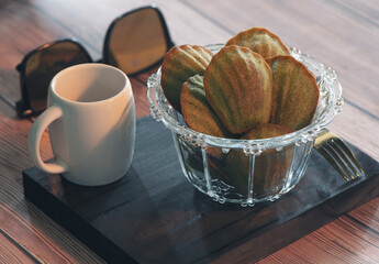 Petite madeleine in glass bow on wooden table.

