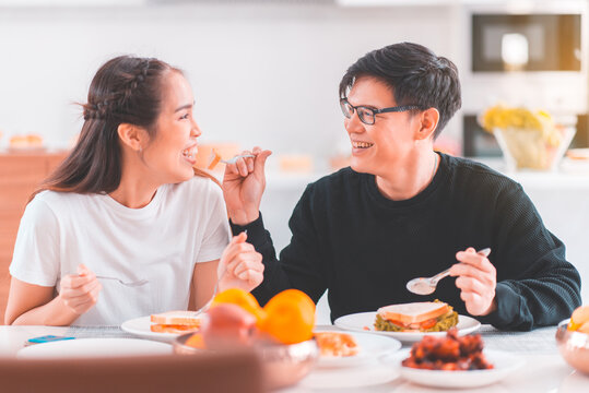 Happy Asian Couple In Love Eating Meal Together At Home