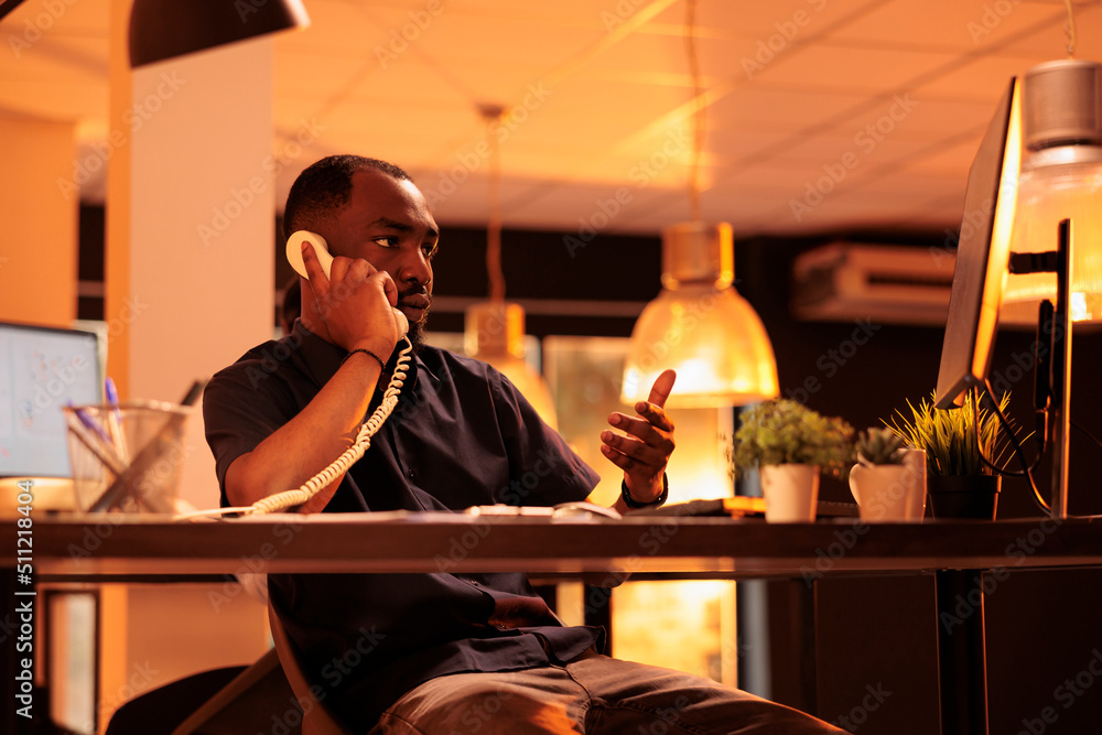Poster office worker answering landline phone call to talk to manager about paperwork report on computer. c