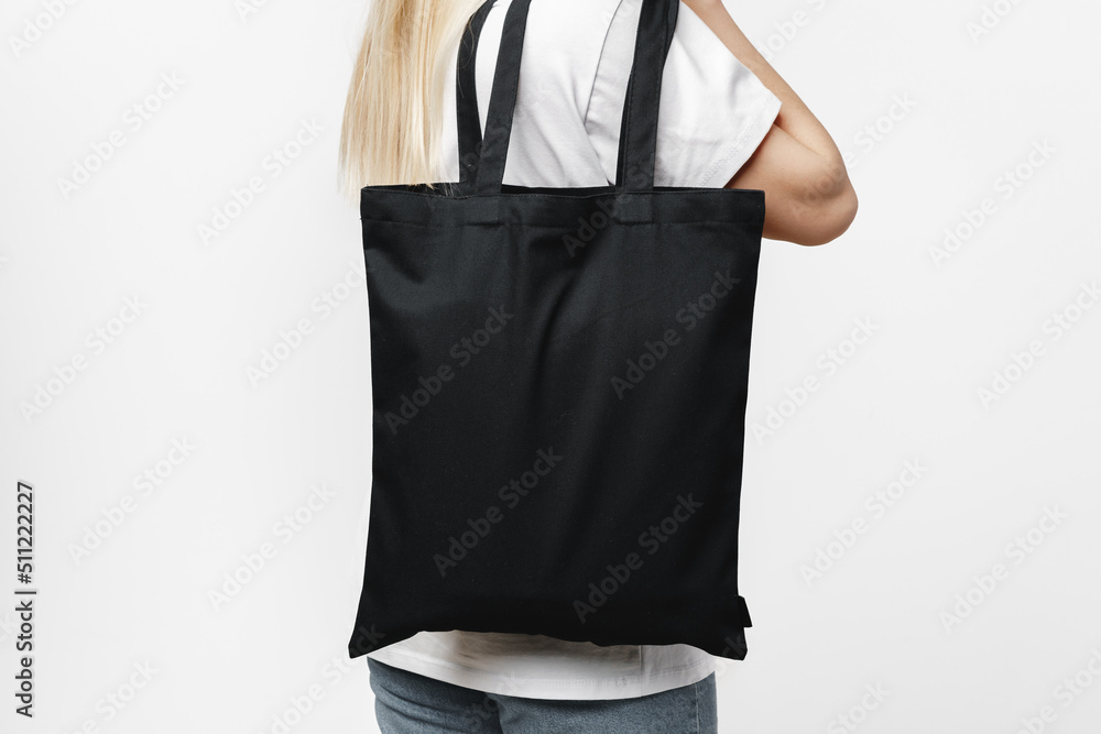 Wall mural Female holding black cotton bag in her hands on white background