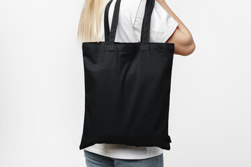 Female holding black cotton bag in her hands on white background