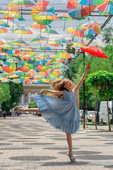 Pretty kid girl jumping while holding a red umbrella. Beautiful child flying