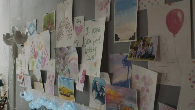Tracking view of many pictures, drawings and get well soon postcards on wall of room at daytime, dripper