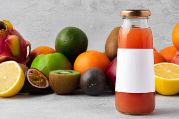 Various fruits and freshly squeezed fruits juice in bottle on gray background