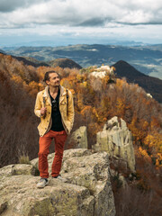 Traveler is standing on high rock, enjoying the view and looking up. Travel and hiking concept in autumn time.