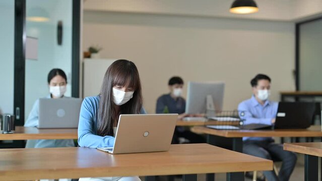 Young Asian Employee With Face Masks In The Office After Lockdown, New Normal And Return To Work Concept