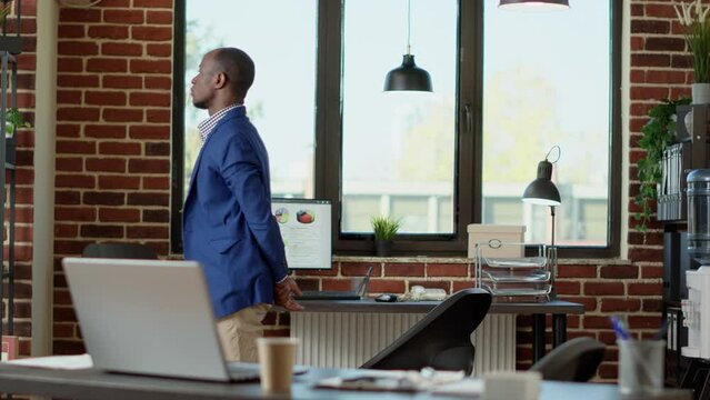 African American Consultant Waiting In Company Office To Receive Good Business News. Nervous Project Manager Pacing Around Startup Workplace To Find Out About Presentation Solution.