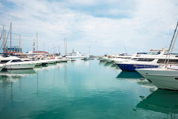 Luxury yachts docked in sea port. Marine parking of modern motor boats and azure water. Tranquility, relaxation and fashionable vacation. White yachts and sailboats moored in marina, summer season.