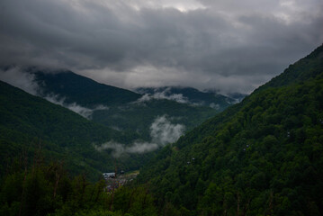 Spring morning at mountains and clouds. Atmospheric landscape with trees and low clouds on cloudy sky. Awesome mountain scenery.