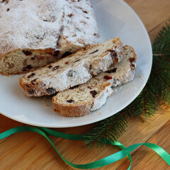 Traditional german sweet bread with raisins and candied fruits called Stollen on a plate on wooden table 