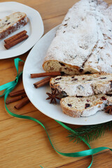 Traditional german sweet bread with raisins and candied fruits called Stollen on a plate on wooden table 
