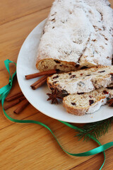 Traditional german sweet bread with raisins and candied fruits called Stollen on a plate on wooden table 