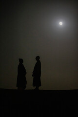 Buddhist monks standing under the moonlight during a zen retreat in the Sahara, Morocco. 25.02.2017