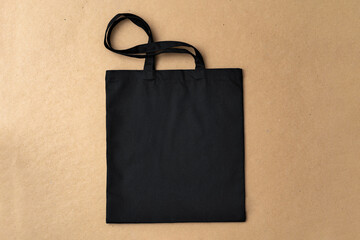 Black textile shopping bag on beige background flat lay