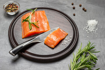 Pieces of salmon and kitchen knife on cutting board.