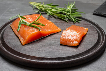 Pieces of salmon and sprigs of rosemary on cutting board.