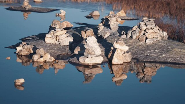 A meditation garden. Small stone cairns are arranged in the middle of the small pond. Slow-motion, pan right.